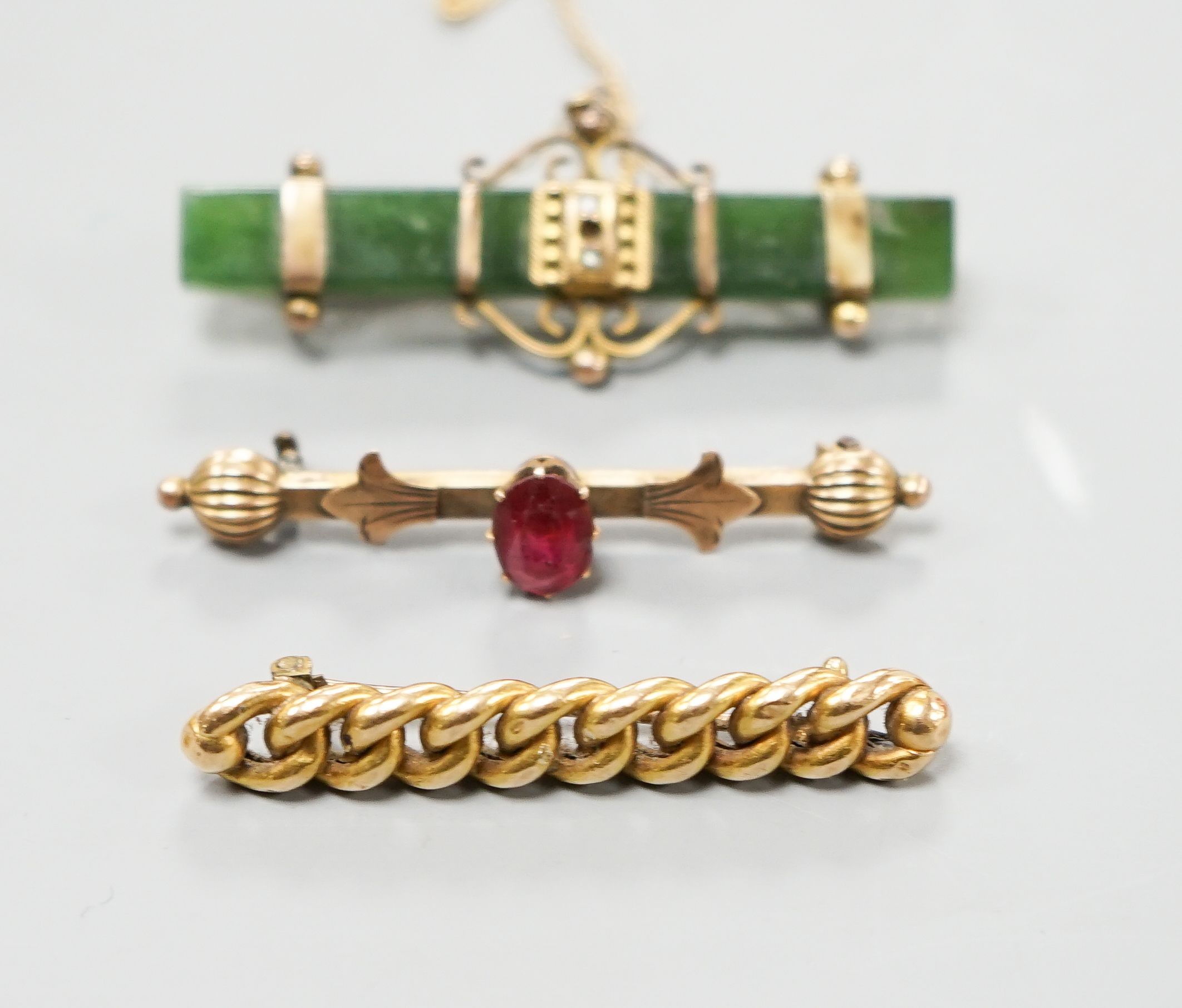 An Edwardian 15ct interwoven bar brooch, 45mm gross 4.2 grams, a mounted nephrite bar brooch and one other bar brooch.